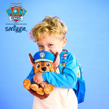 A young child wearing a blue long-sleeve shirt and a blue backpack holds a Paw Patrol plush toy against their face, set against a solid blue background with Smuggle and Paw Patrol logos.